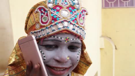 Handheld-close-up-of-young-girls-dressed-as-Hindu-God-talking-communication-technology-on-a-smart-mobile-phone-and-look-at-the-camera-happy-joy-content