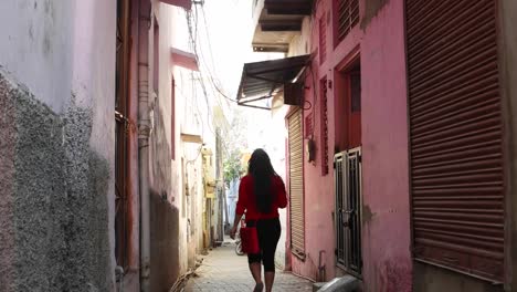 Indische-junge-weibliche-Touristen-durch-die-Straßen-kleine-Rampen-eng-Stadt-ländlichen-Einstellung-voll-gepackten,-handheld-folgen