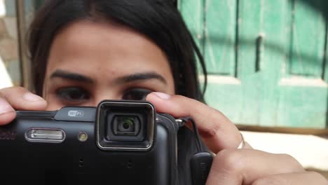 Indian-urban-tourist-young-woman-takes-photos-videos-on-her-point-and-shoot-camera-on-the-busy-corwded-streets