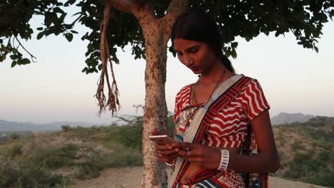 Handheld-shot-of-woman-texts-message-share-photo-video-smiles-mobile-phone-communicates-device-connectivity-signal-wireless-at-sunset-on-hill-outdoor-nature-hot-summer-magic-hour-beautiful-low-angle