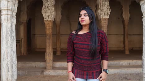 Young-woman-looks-at-the-camera-and-reacts-surprised-sacred-hands-on-her-face-in-an-old-ruins-of-a-temple-complex-in-the-holy-Hindu-city-of-Pushkar-in-the-state-of-Rajasthan-India