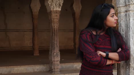 Handheld-shot-of-woman-waits-looks-search-far-around-at-her-smart-watch-phone-mobile-touch-screen-smiles-finds-at-camera--in-old-ancient-Hindu-temple-facade-backdrop-enter-frame-late-lover-pleased