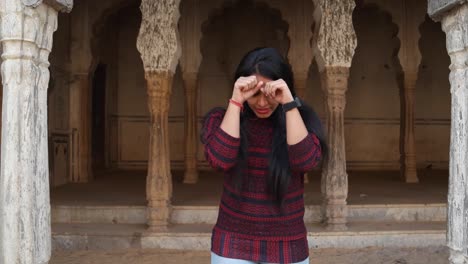 Handheld-shot-of-woman-pissed-angry-bad-mood-smart-watch-late-nods-surprised-smiles-joke-kidding-joy-hands-on-face--looks-at-camera-in-old-ancient-Hindu-temple-facade-complex-holy-city-move-to-frame