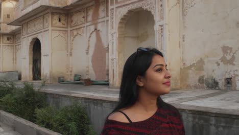 Handheld-shot-of-tourist-woman-in-front-of-Indian-Hindu-temple-taking-selfie--photo-video-on-her-mobile-smart-phone-happy-share-facade-architecture-ancient-holy-religious-fort-castle-palace-Rajasthani