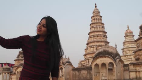 Woman-in-front-of-panoramic-attractive-ornate-temple-fort-palace-complex-from-a-vantage-point-higher-level-taking-selfie-photo-on-mobile-phone-camera-tourist--Hindu-religious-massive-love-handheld-pov