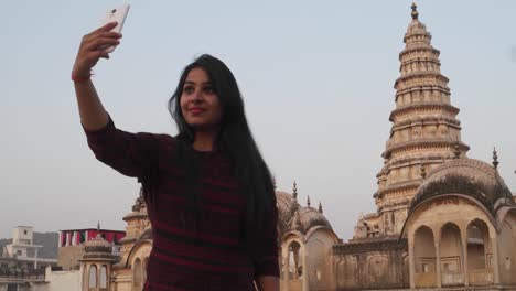 Mujer-delante-panorámica-templo-ornamentado-atractivo-fuerte-complejo-del-Palacio-de-un-nivel-más-alto-de-mirador-tomando-foto-selfie-en-teléfono-móvil-cámara-turismo-amor-masivo-religioso-hindú-mano-pov