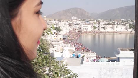 Handheld-Frau-nimmt-Selfie-Foto-Video-mit-ihrem-mobilen-Handy-Gerät-von-einem-Panorama-Aussichtspunkt-Blick-des-Heiligen-Pushkar-See,-eine-heilige-Stadt-für-Hindu-Pilger-Mela-Festival-Baden-Ghats-Tempel