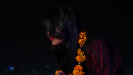 Mujer-joven-con-las-manos-juntas-saluda-namaste-como-sacerdote-hindú-guirnalda-de-flores-de-caléndula-naranja-en-sus-cuello-sonrisas-respeto-creyente-religión-ofrece-las-manos-junto-al-lago-sagrado-de-Pushkar-mano