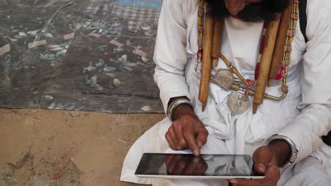 Man-being-helped-and-instructed-to-use-a-touch-screen-tablet,-Indian-Rajasthani-elderly-male-with-big-moustache-wearing-Traditional-attire-and-ethic-turban