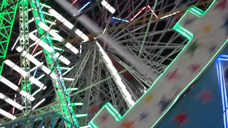 Carnival-with-ferris-wheel,-bright-colourful-lights,-car-carousel-at-night-closeup