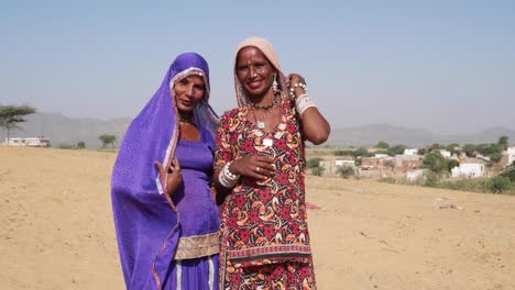 Kippen-Sie-bis-zu-zwei-Freunde-kichern-in-traditioneller-Kleidung-in-Wüsten-von-Pushkar,-Rajasthan