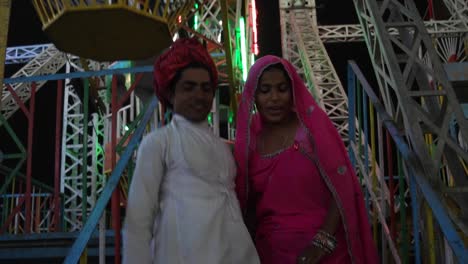 Pareja-India-goza-de-noria-paseo-en-vestidos-tradicionales-en-la-Pushkar-Mela,-un-carnaval-de-Rajasthán,-la-India