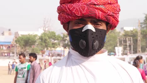 Indian-man-with-red-turban-turns-and-is-wearing-a-pollution-mask-at-a-Fairground-in-India