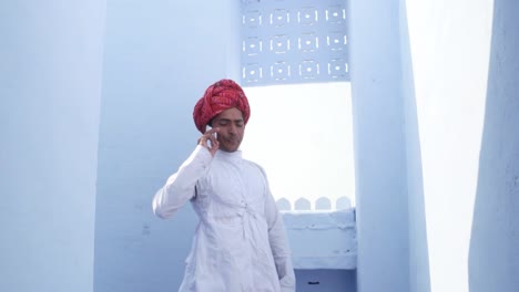 Tilt-down-to-a-handsome-man-in-traditional-Indian-turban-and-clothing-talking-on-the-phone-with-surreal-lighting