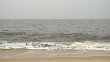 Olas-rompiendo-en-una-hermosa-playa-en-un-día-brumoso-en-Varkala,-India.