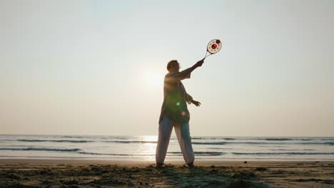 Ältere-Frau-praktizieren-Tai-Chi-Ballon-Ball-am-Strand-bei-Sonnenuntergang