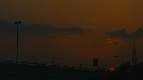 Zeitraffer-Aufnahme-von-Fahrzeugen,-die-auf-der-Brücke-in-der-Dämmerung,-Sonnenuntergang,-Delhi,-Indien