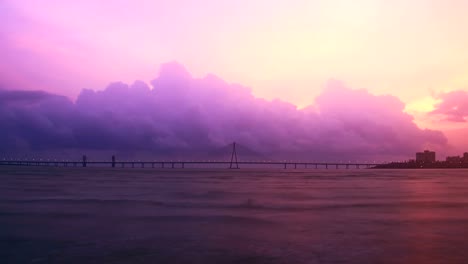 Evening-to-night-time-lapse-shot-of-Bandra--Worli-sea-link-(bridge)-over-the-Arabian-sea-with-the-cloud-formation-and-changing-skyline-in-the-background,-Mumbai,-india