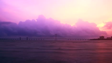 Abend-zur-Zeit-verfallen-Nachtaufnahme-von-Bandra---Worli-Sea-Link-(Brücke)-über-das-Arabische-Meer-mit-der-Wolkenbildung-und-wechselnden-Skyline-im-Hintergrund,-Mumbai,-Indien