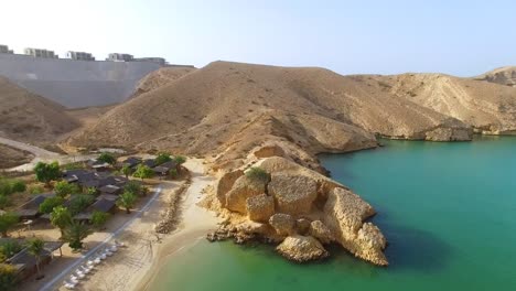 Vista-aérea-de-la-bahía-de-Muscat,-resort-de-buceo,-excursión-de-un-día-y-zona-de-relax,-de-cristalinas-aguas-del-océano-Índico,-la-playa-y-la-laguna-azul,-Omán,-Sultanato-de-la-Península-Arábiga,-4k-UHD