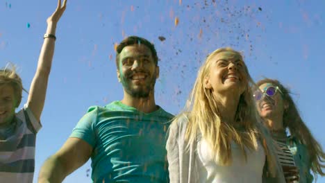 Low-Angle-Shot-of-Multi-Ethnic-Diverse-Group-of-Young-People-Jump-and-Throw-Colorful-Powder-in-the-Air-in-Celebration-of-Holi-Festival.-They-Have-Enormous-Fun-on-this-Sunny-Day.