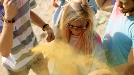 High-Angle-Shot-von-einem-blonden-Mädchen-werfen-bunte-Pulver-in-die-Menschenmenge-inmitten-hinduistischen-Holi-Fest-feiern.-Sie-haben-enorm-viel-Spaß-an-diesem-sonnigen-Tag.