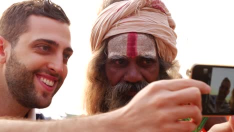 Tourist-taking-a-selfie-with-Sadhu---Holy-Man,-in-Varanasi,-India