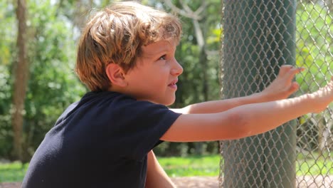 Kind-möchte-die-Aufmerksamkeit-der-Tiere-hinter-Gittern-Käfig-gesperrt.-Kleiner-Junge-Rasseln-Käfig-fordern-Affen-zu-kommen