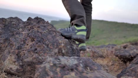 Eine-männliche-Wanderer-oder-Trekker-in-Schuhen-und-Hosen-zu-Fuß-auf-einem-Berggipfel