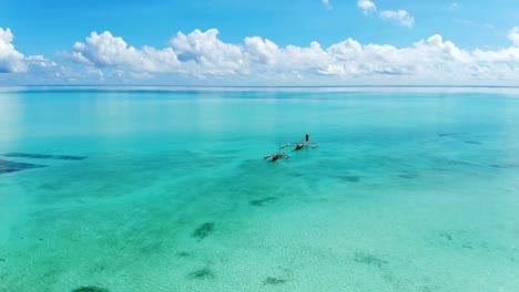 Aerial-view-of-a-fisherman-sails-on-a-wooden-boat-on-clear-blue-water-along-a-tropical-exotic-beach-in-Africa