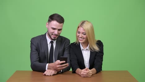 Young-happy-business-couple-using-phone-together