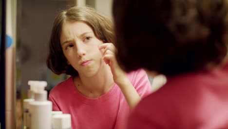 teenage-girl-looking-the-the-bathroom-mirror-checking-her-face