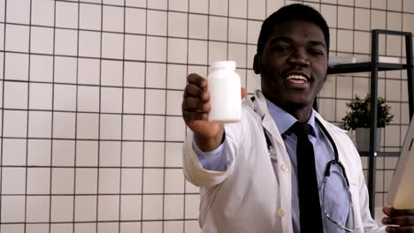 Smiling-doctor-holding-up-a-bottle-of-tablets-or-pills-with-a-blank-white-label-for-treatment-of-an-illness-or-injury