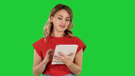 Moderatorin-Frau-im-roten-T-shirt-hält-einen-Tablet-drehen-Seiten-und-Gespräch-mit-Kamera-auf-einem-Green-Screen,-Chroma-Key