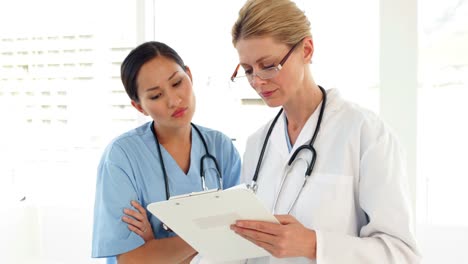 Medical-workers-looking-over-a-file-and-looking-at-camera