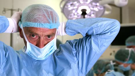 Medical-professor-in-surgical-gear-putting-on-mask