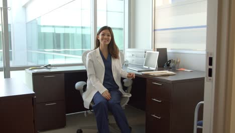 Portrait-Of-Female-Doctor-Working-At-Desk-In-Office