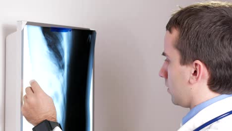Ein-junger-Arzt-untersucht-die-Ergebnisse-der-Röntgenaufnahme-eines-Patienten-an-der-Wand.-Analysiert-den-Brustkorb-und-Rippen