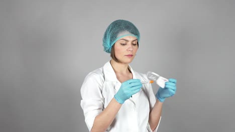 Young-female-doctor-in-gloves-holding-a-syringe-isolated-on-grey-background.-Healthcare-concept.-Shot-in-4k