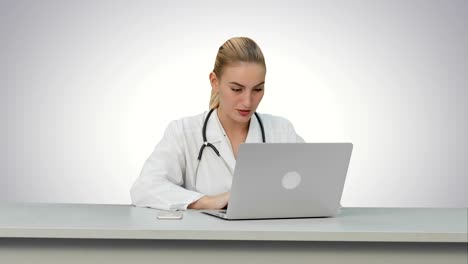 Seriouse-female-doctor-working-on-her-laptop-on-white-background