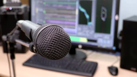 Microphone-on-the-background-of-the-computer-monitor.-Home-recording-Studio.-Close-up.-The-focus-in-the-foreground.-Blurred-background.-Software-for-recording-and-editing-sounds.-4K,-UHD,-Ultra-HD