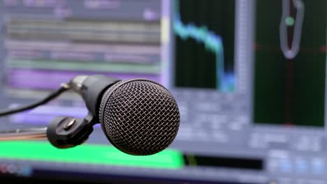 Microphone-on-the-background-of-the-computer-monitor.-Home-recording-Studio.-Close-up.-The-focus-in-the-foreground.-Blurred-background.-Software-for-recording-and-editing-sounds.-4K,-UHD,-Ultra-HD