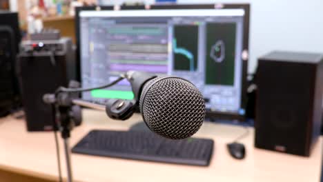 Microphone-on-the-background-of-the-computer-monitor.-Home-recording-Studio.-Close-up.-The-focus-in-the-foreground.-Blurred-background.-Software-for-recording-and-editing-sounds.-4K,-UHD,-Ultra-HD