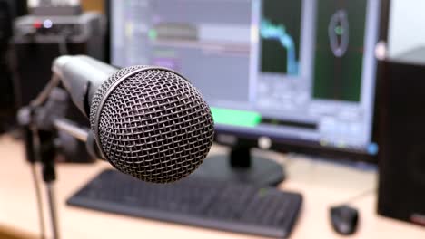 Microphone-on-the-background-of-the-computer-monitor.-Home-recording-Studio.-Close-up.-The-focus-in-the-foreground.-Blurred-background.-Software-for-recording-and-editing-sounds.-4K,-UHD,-Ultra-HD