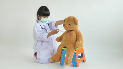 Asiatischen-Arzt-mit-Bär-Puppe-spielendes-Kind
