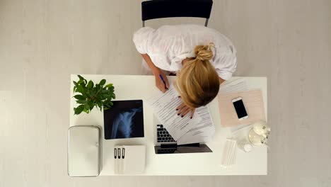 Médico-joven-y-profesional-trabaja-con-un-montón-de-documentos-en-la-oficina