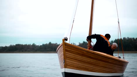 Holzboot-mit-zwei-Männern,-die-versuchen,-Mast-gesetzt