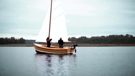 Velero-de-madera-con-dos-hombres-tratando-de-instalar-el-mástil