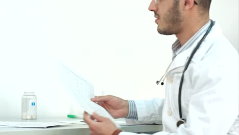 Young-doctor-in-glasses-showing-medical-results-to-his-patient