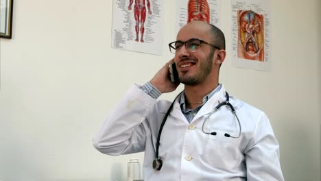 Sonriente-médico-varón-tener-una-conversación-de-teléfono-alegre